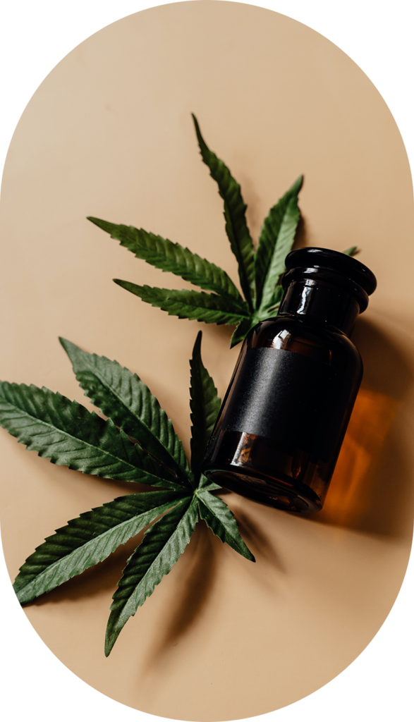 frasco de cristal junto a hojas de cannabis